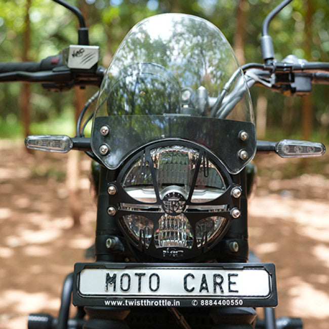 Motorcycle front view with windshield, headlight grill, and Moto Care license plate outdoors