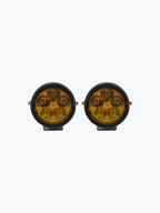 Pair of round yellow motorcycle LED auxiliary lights with black housing on white background