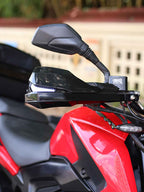 Close-up of red motorcycle handlebar with black mirror and handguard