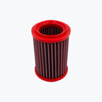 Red cylindrical motorcycle air filter with pleated mesh element on a light background