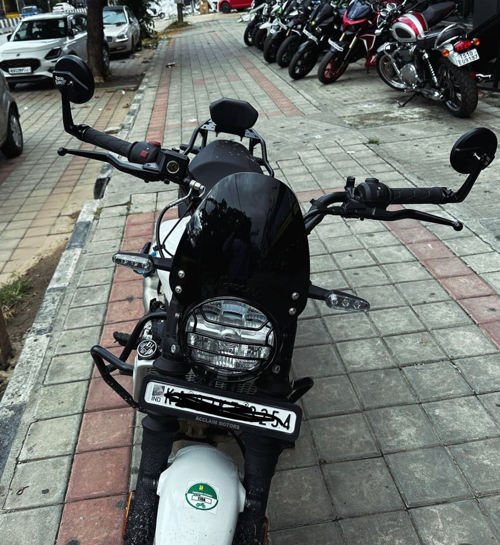 Front view of a parked black and white motorcycle on a city sidewalk, with other bikes lined up in the background.
