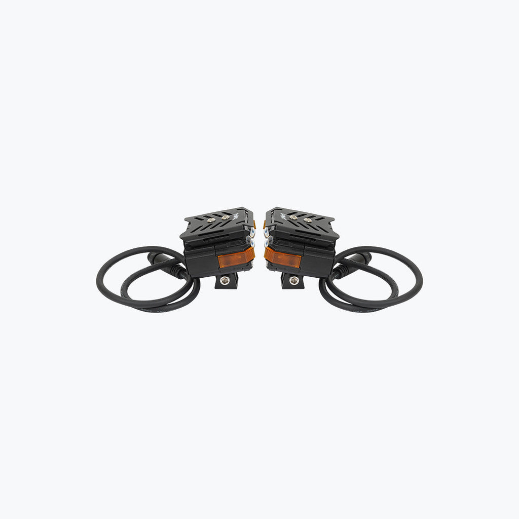 Pair of black motorcycle LED fog lights with wiring and orange reflectors on white background