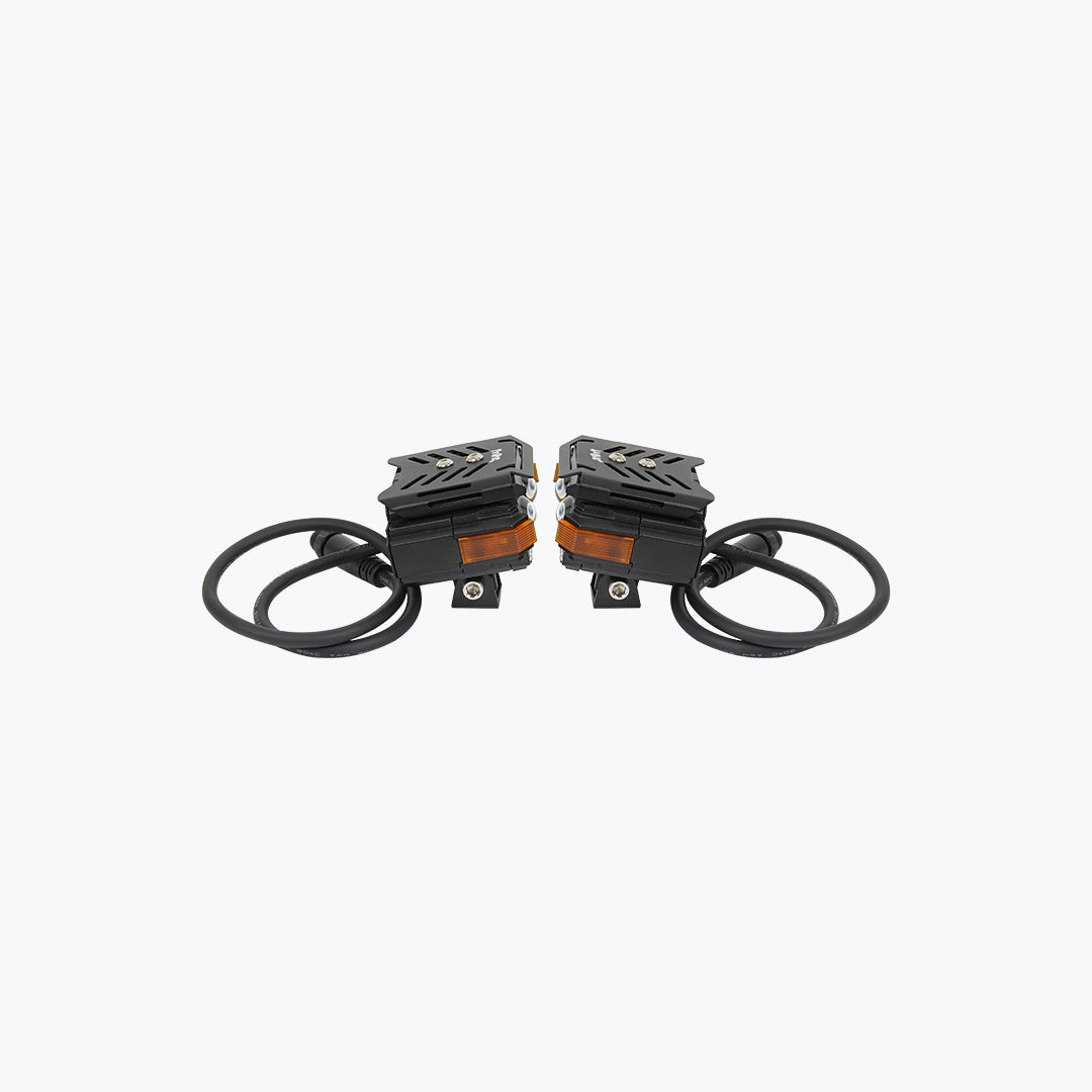 Pair of black motorcycle LED fog lights with wiring and orange reflectors on white background