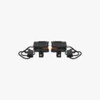 Pair of black motorcycle LED auxiliary lights with amber accents and mounting brackets