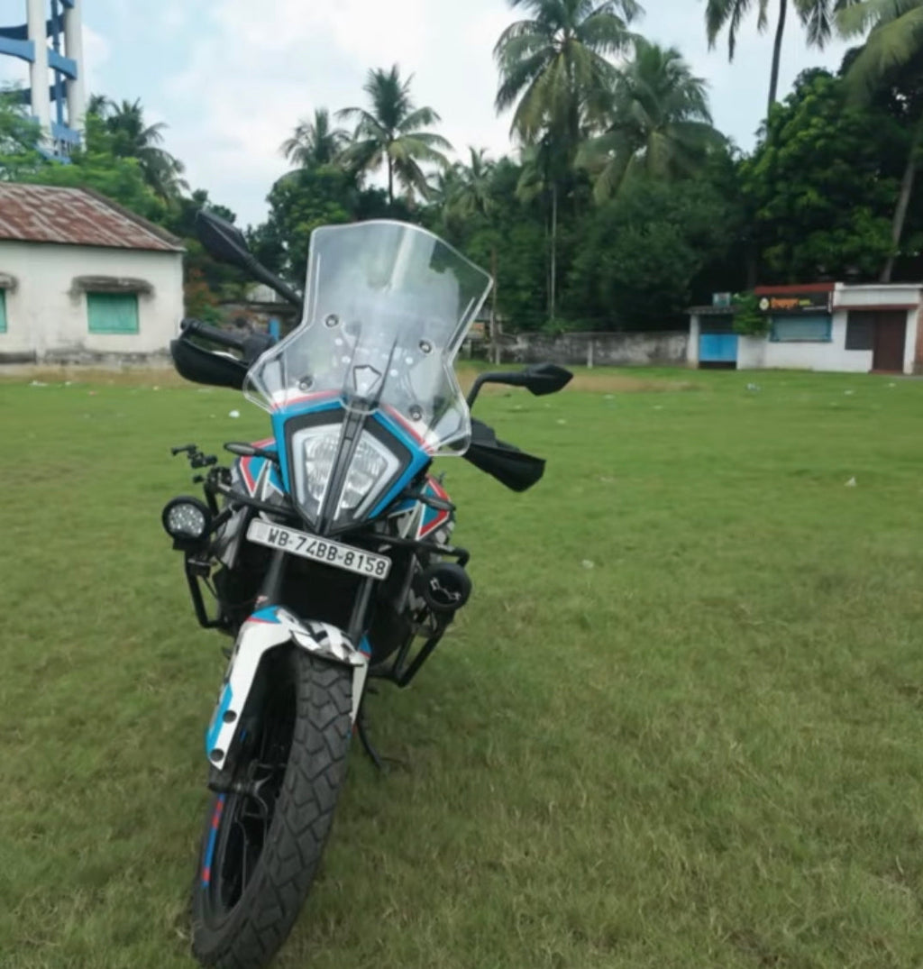 Adventure touring motorcycle with windshield parked on grassy field, palm trees in background