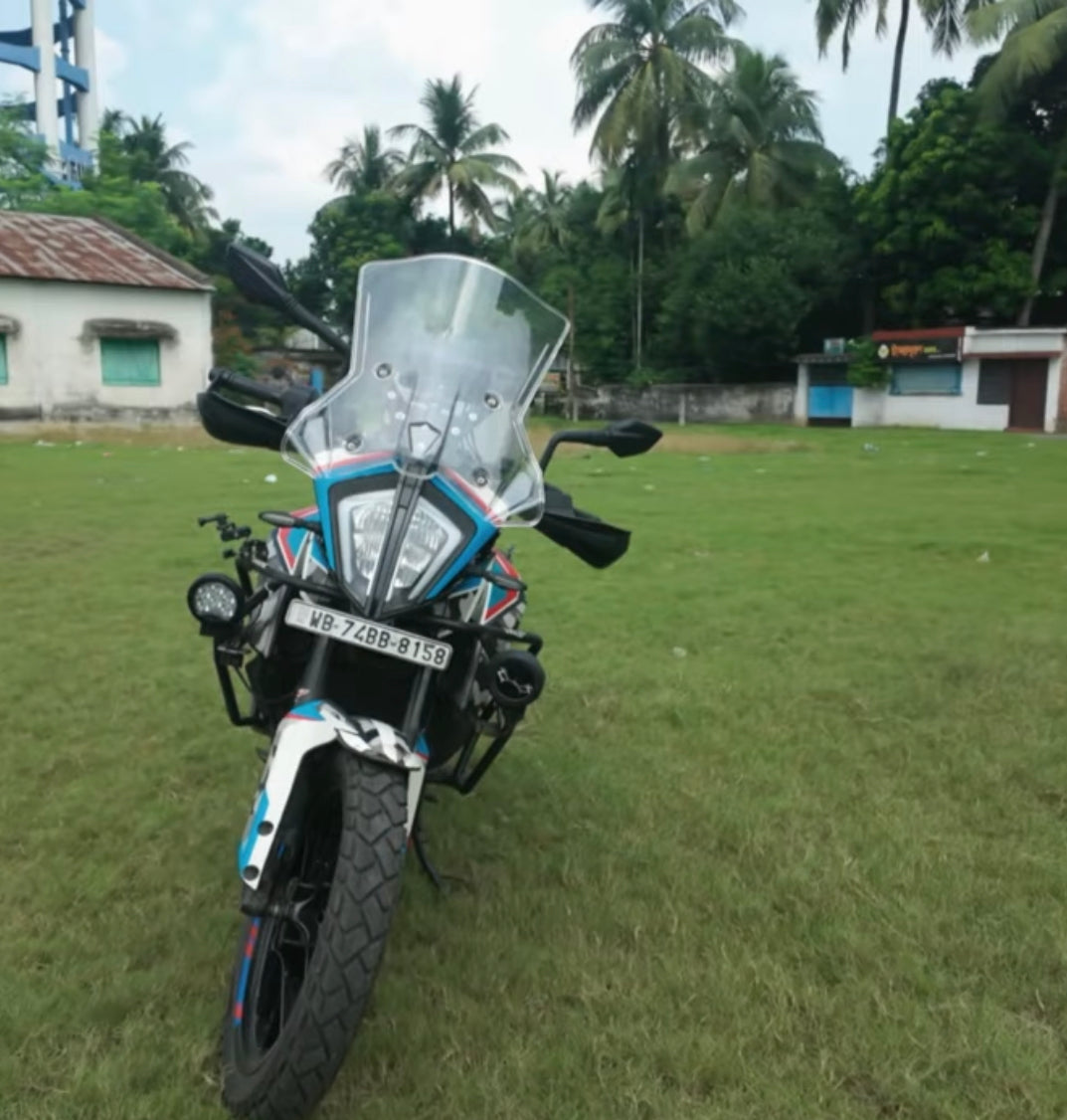 Adventure touring motorcycle with windshield parked on grassy field, palm trees in background
