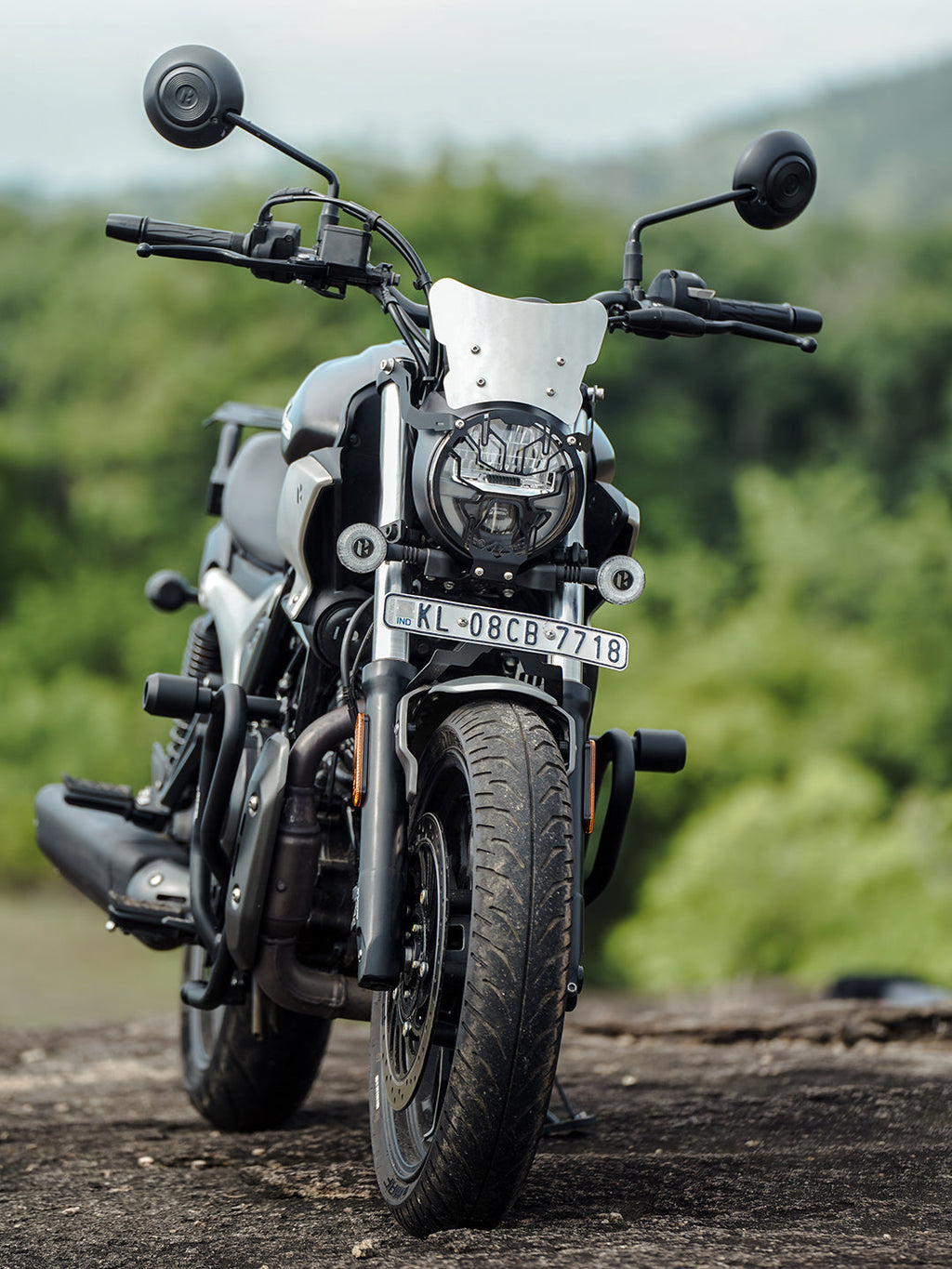 Stylish black motorcycle with metal windshield and round mirrors parked outdoors