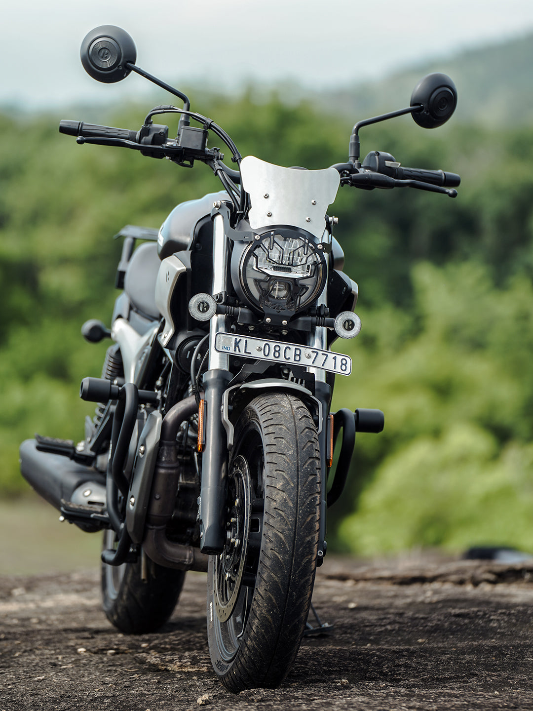 Stylish black motorcycle with metal windshield and round mirrors parked outdoors