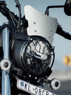 Motorcycle front view with headlight grill, silver windscreen, and license plate