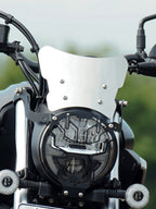 Close-up of motorcycle headlight with protective grille and metal windscreen