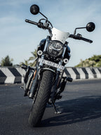 Front view of a black motorcycle with windshield parked on urban street
