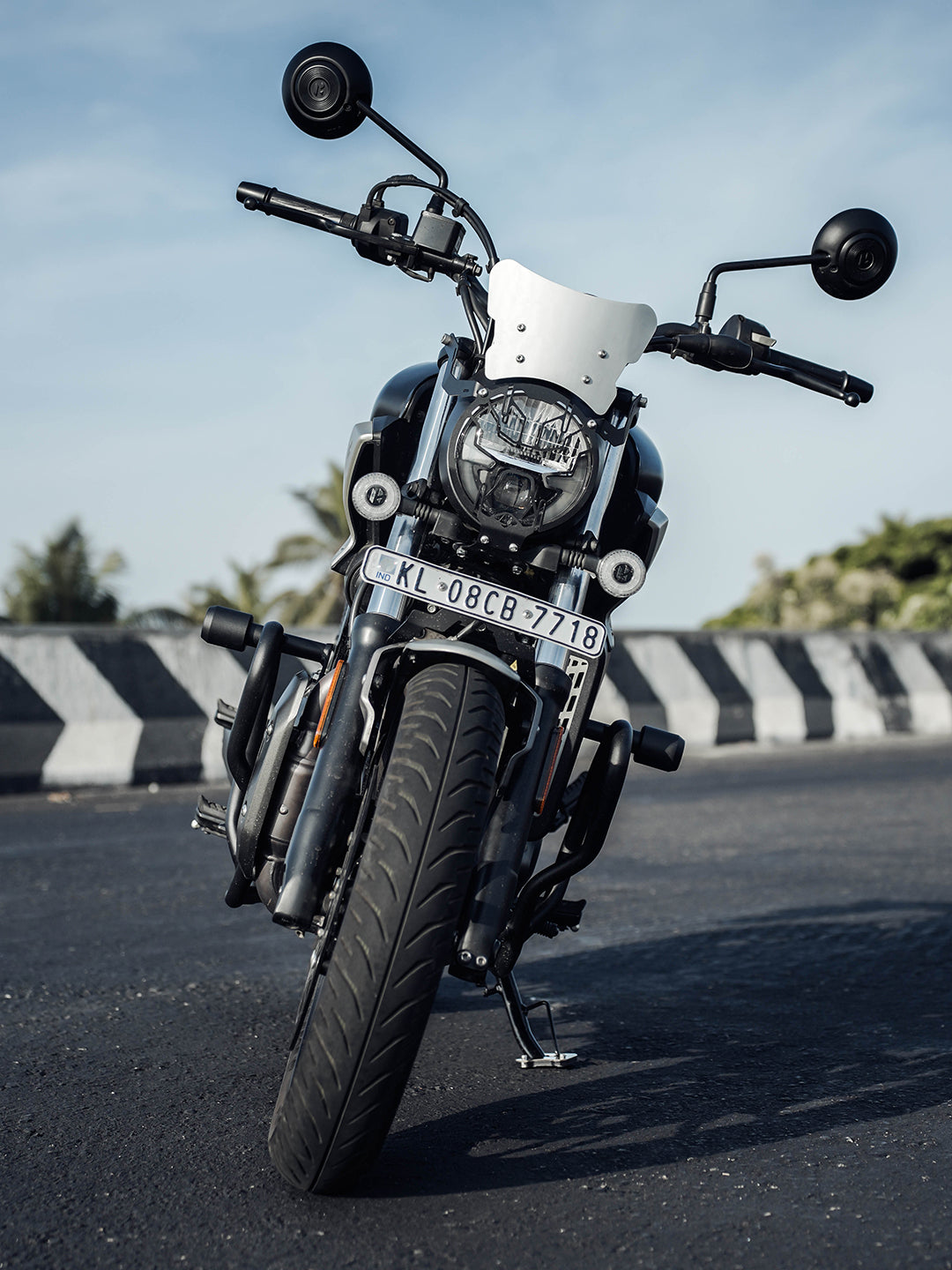 Front view of a black motorcycle with windshield parked on urban street