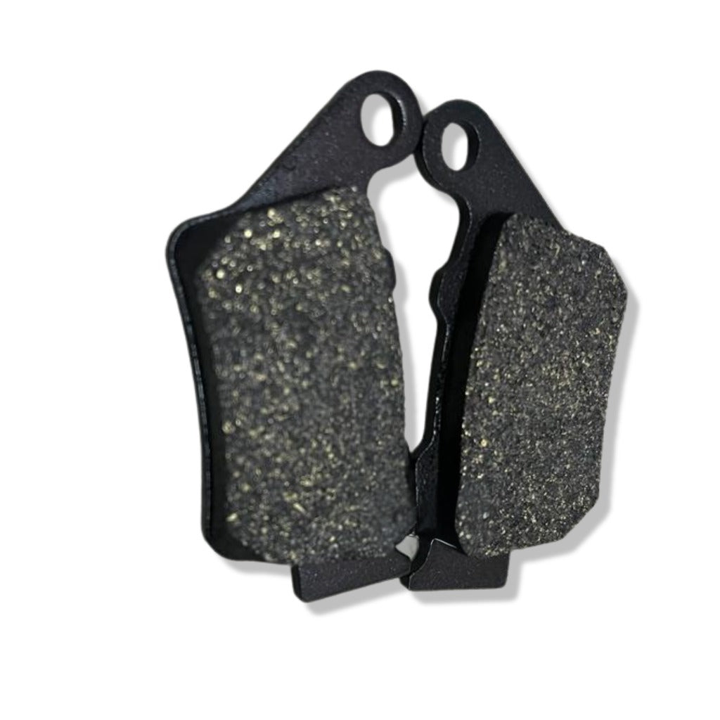 Close-up of two black motorcycle brake pads with textured friction surfaces