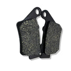 Close-up of two black motorcycle brake pads with textured friction surfaces