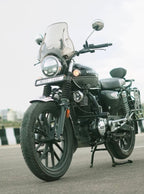 Black Honda motorcycle with windshield parked on road, side view, urban background