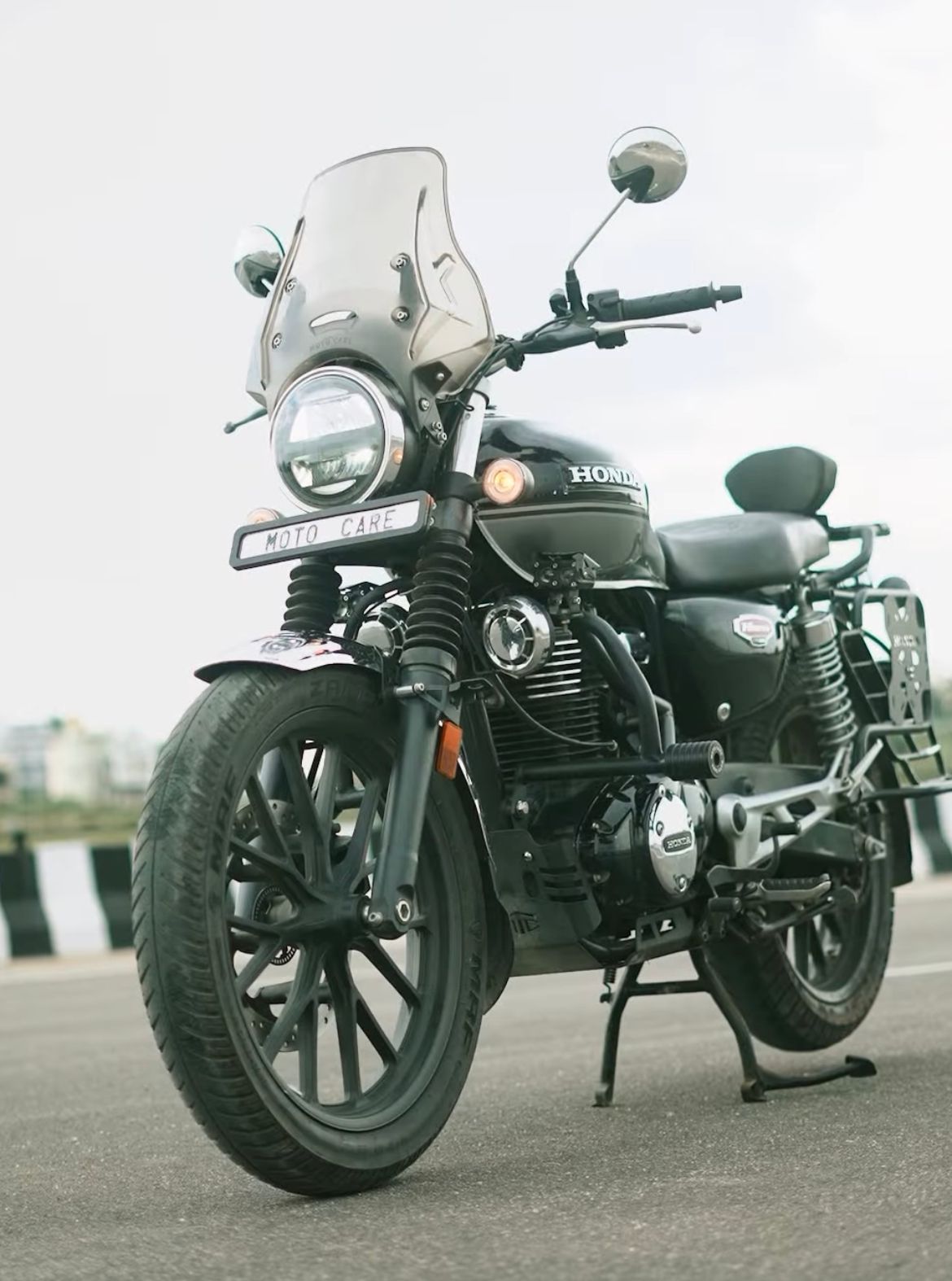 Black Honda motorcycle with windshield parked on road, side view, urban background