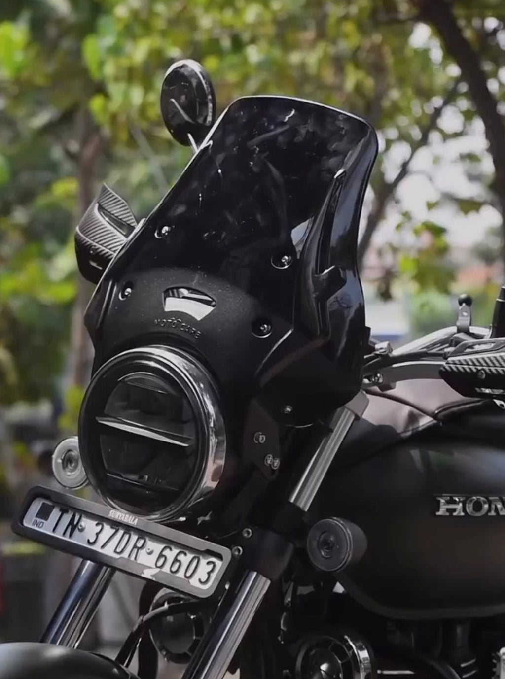 Close-up of Honda motorcycle with black windscreen, round LED headlight, and license plate