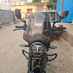 Front view of a black motorcycle with windshield and round LED headlight on urban street