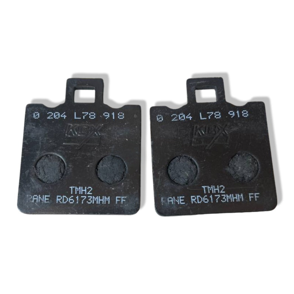 Pair of black motorcycle brake pads with model numbers and grooves visible on white background