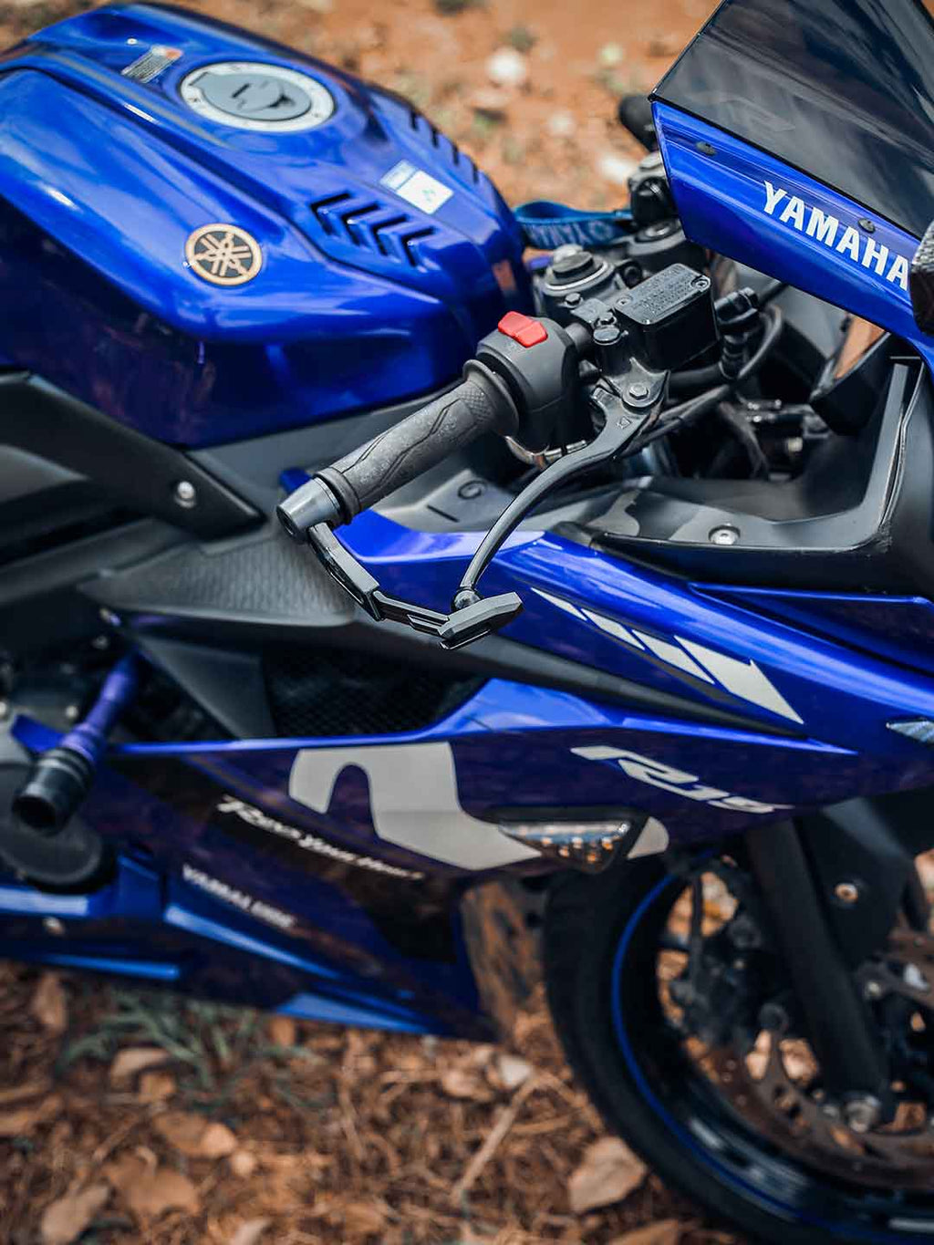 Close-up of Yamaha blue motorcycle handlebar with lever guard on forest ground