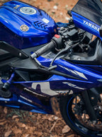 Close-up of Yamaha blue motorcycle handlebar with lever guard on forest ground