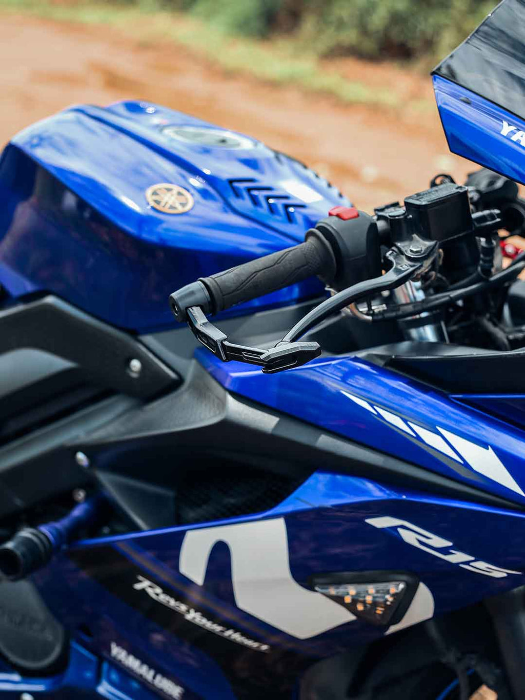 Close-up of motorcycle lever guard on blue Yamaha sportbike handlebar outdoors