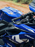 Close-up of motorcycle lever guard on blue Yamaha sportbike handlebar outdoors