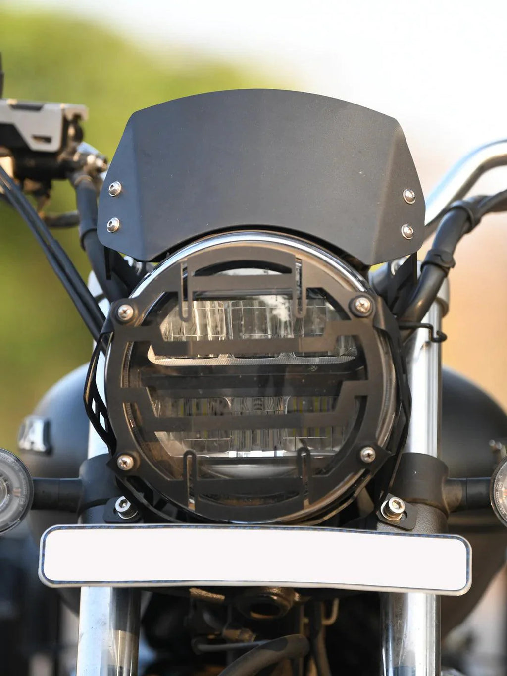 Black metal motorcycle headlight visor and grill with clear LED headlamp, front view