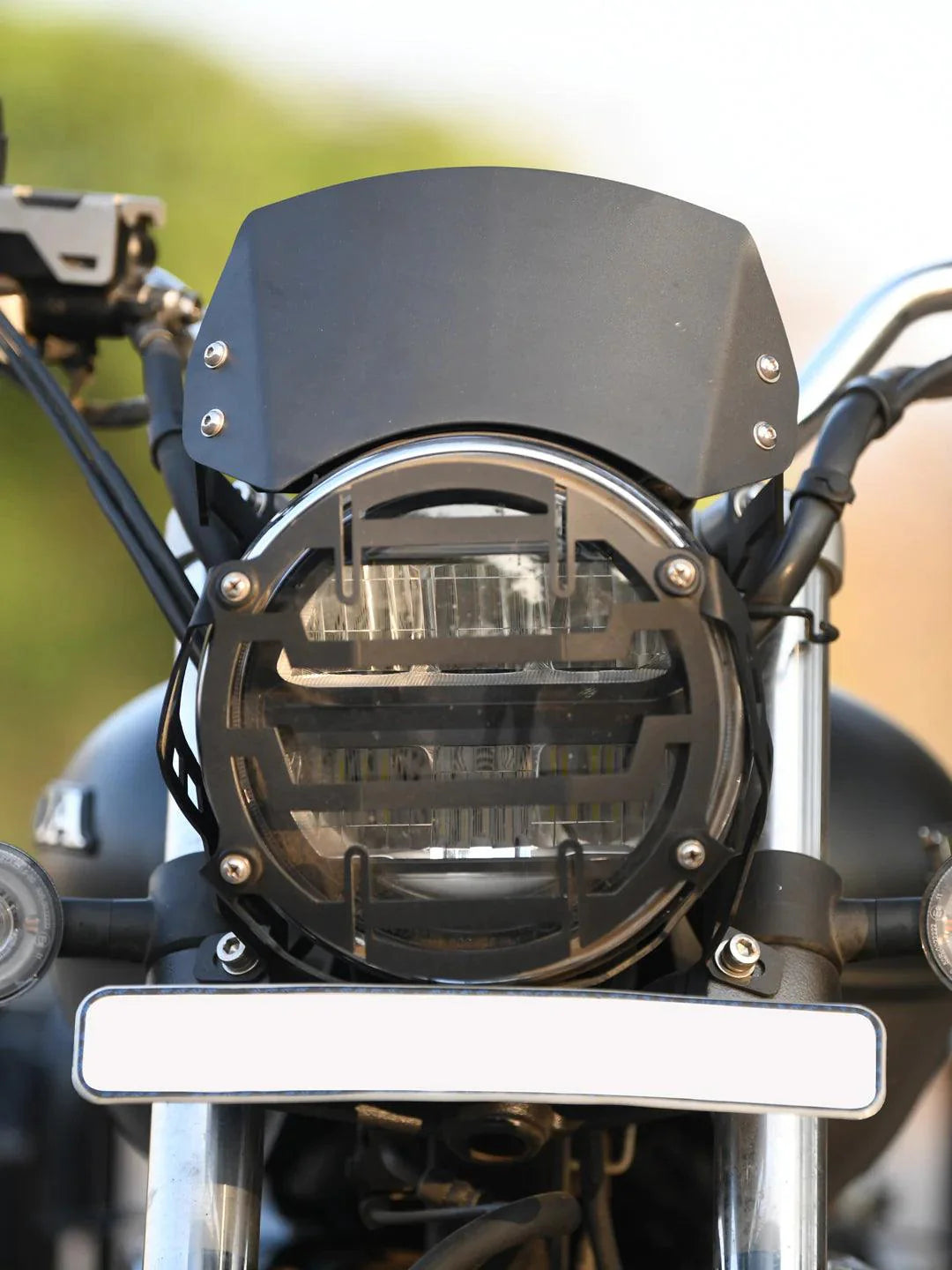 Black metal motorcycle headlight visor and grill with clear LED headlamp, front view