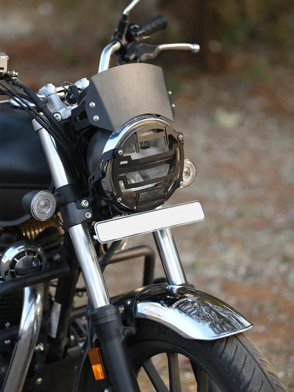 Close-up of a motorcycle front with metal headlight visor and black headlight grill.