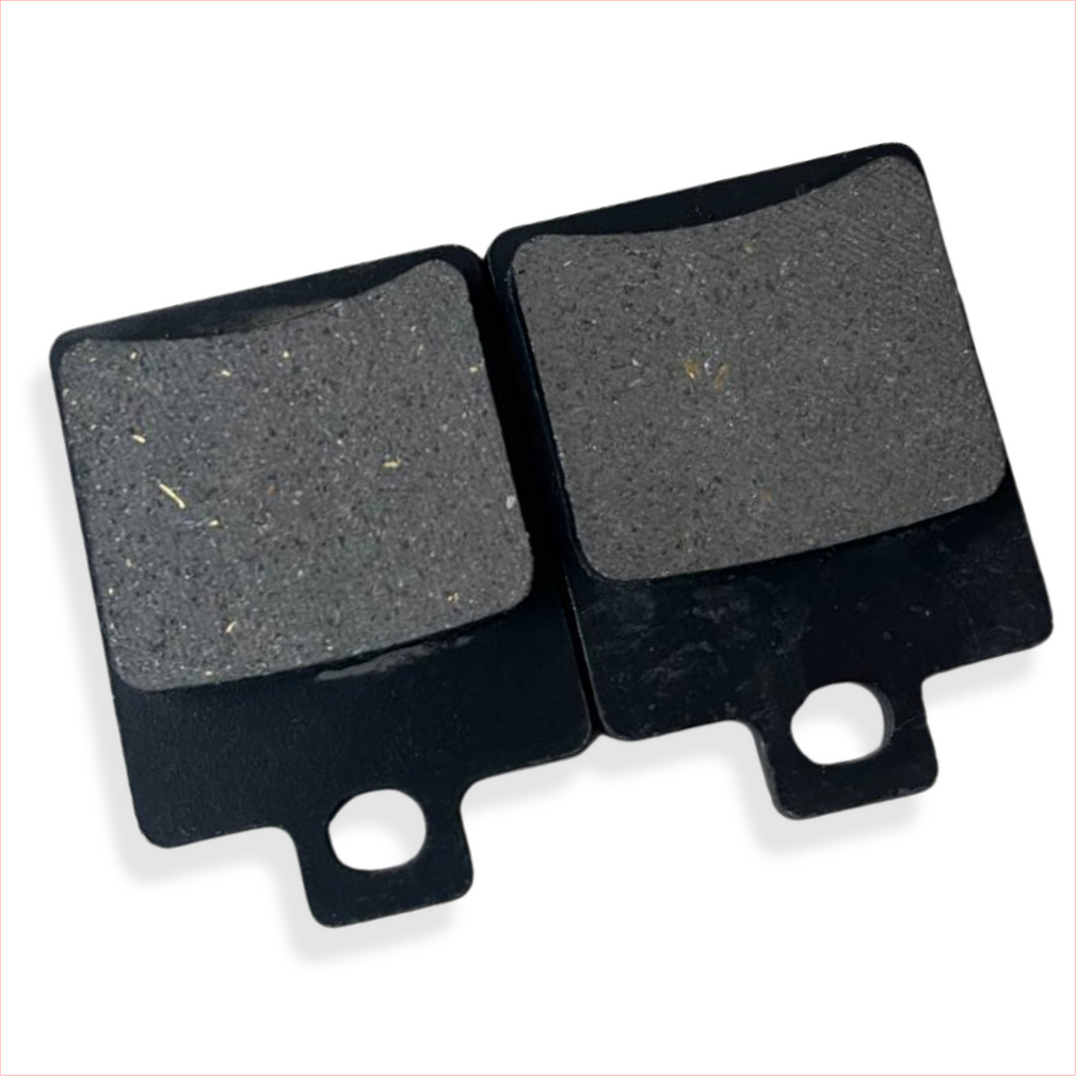 Close-up of two rectangular motorcycle brake pads with black metal backing.