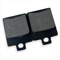 Close-up of two rectangular motorcycle brake pads with black metal backing.