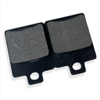 Close-up of two rectangular motorcycle brake pads with black metal backing.