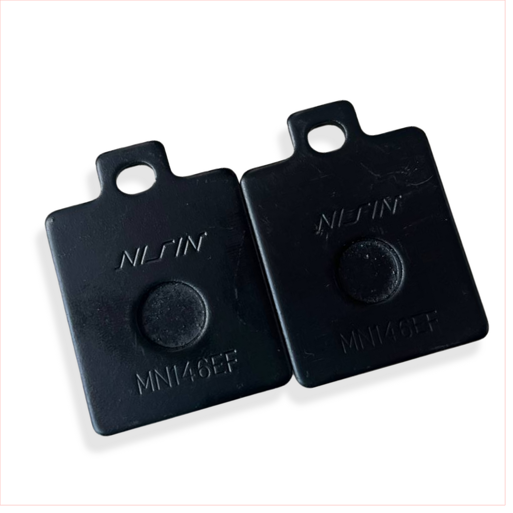 Black Nissin MN146EF motorcycle brake pad spacers on white background