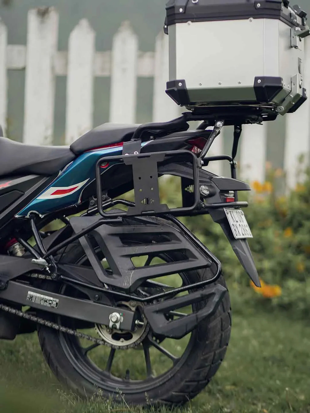 Motorcycle rear luggage carrier with saddle stay, pannier rack, and top box outdoors